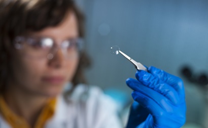 a scientist holds a contact lense with tweazers